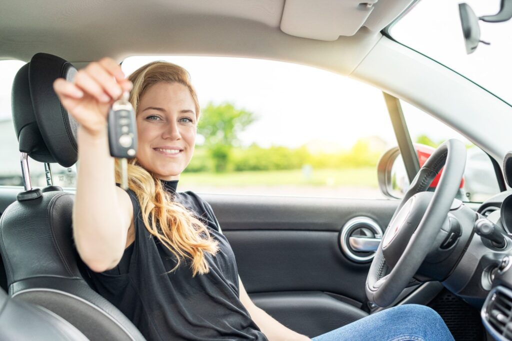 Autorahoitus - nainen ylpeänä uudessa autossa